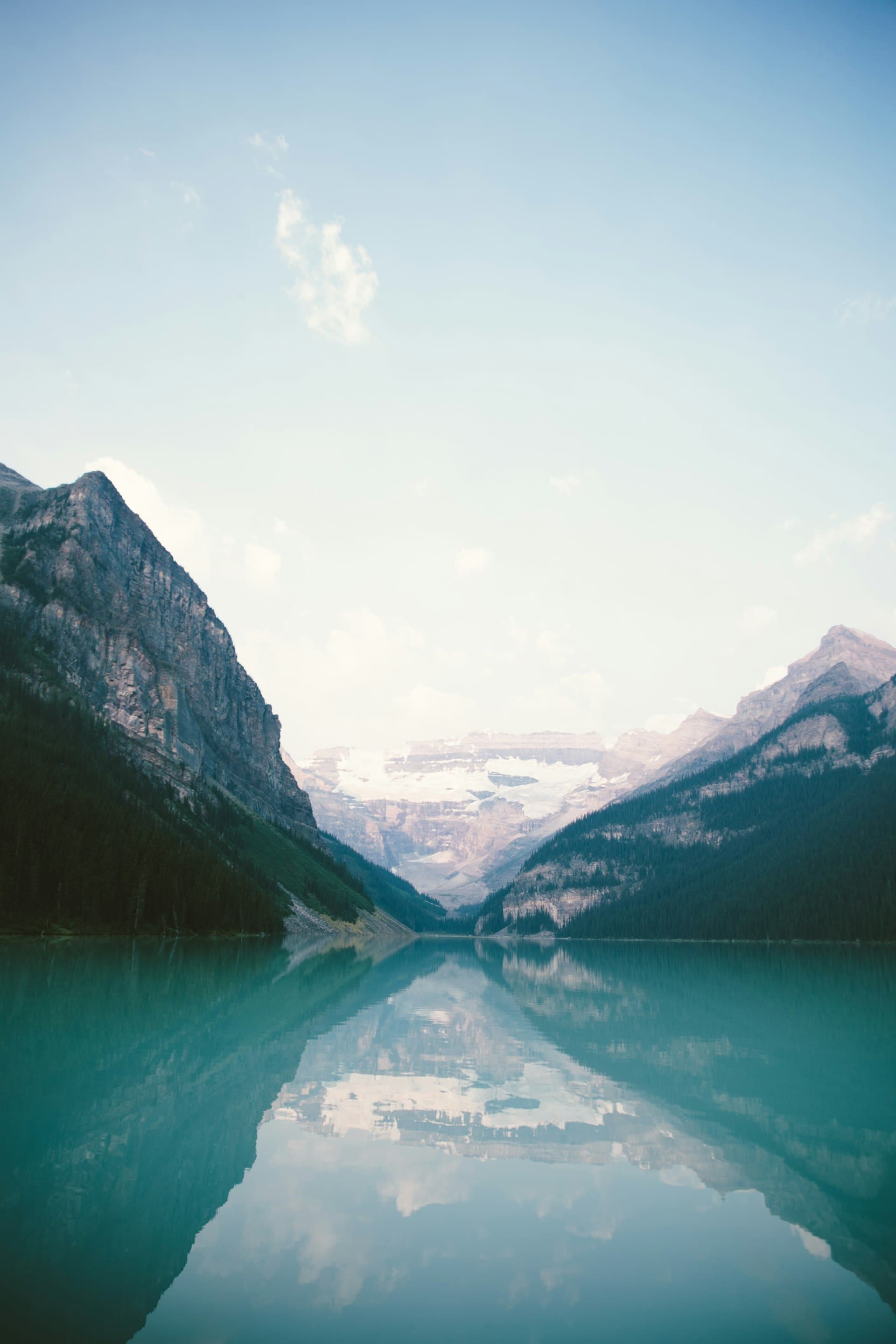 Glacier peaks reflected in still alpine water, sky and mountain merging